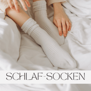 Weiche Schlafsocken an Füßen, gemütlich im Bett liegend, begleitet von zarten Händen, die eine entspannte Atmosphäre erzeugen. Perfekt für eine warme, kuschelige Nachtruhe.