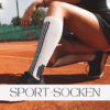 Sportlich gestylte Frau kniet auf einem Tennisplatz, trägt lange weiße Sportsocken mit schwarzen Streifen und schwarze Sneakers. Der Profilname 'Sport-Socken' ist in der Bildmitte platziert.